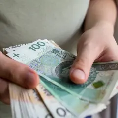 Dłonie trzymające stos banknotów 100 zł.