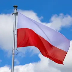 Biało-czerwona flaga Polski powiewa na tle błękitnego nieba z chmurami. Czy 2 maja jest wolny? To pytanie zadają sobie Polacy, ciesząc się świętem narodowym.