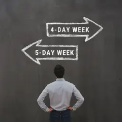 Mężczyzna stoi przed tablicą z dwoma strzałkami: "4-DAY WEEK" i "5-DAY WEEK".