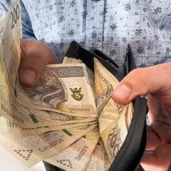 Dłonie trzymające portfel z polskimi banknotami 200 zł.