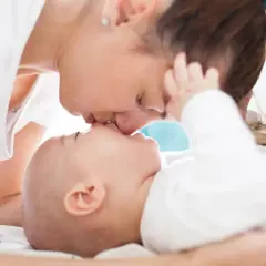Matka całuje swoje dwumiesięczne dziecko w nos.
