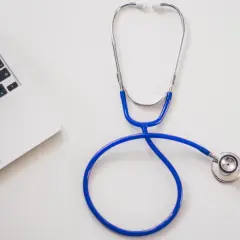 Stetoskop i fragment laptopa na białym tle.