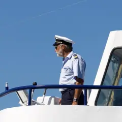 Kapitan na mostku statku, wpatrzony w dal. Zastanawia się, ile zarabia marynarz na jego stanowisku.
