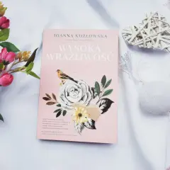 Różowa okładka książki "Wysoka wrażliwość" z motywem kwiatów i ptaszka, otoczona dekoracjami.