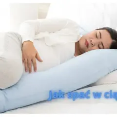 Kobieta w ciąży śpi na boku z poduszką ciążową.