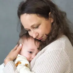 Kobieta tuli dziecko na tle szarej ściany.
