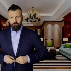 Mężczyzna w garniturze zapina marynarkę w eleganckim salonie.