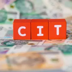 Czerwone klocki z literami "C", "I", "T" leżą na banknotach. Podatek CIT to ważna kwestia dla firm.