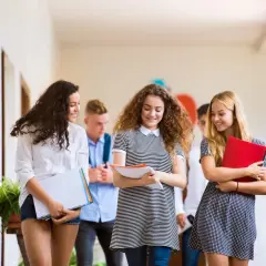 Uczniowie w korytarzu, dyskutujący o tym, czy można iść do szkoły policealnej po studiach.