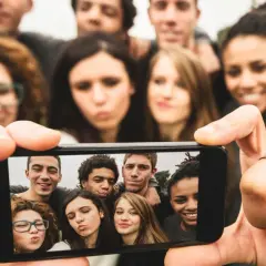 Grupa młodych ludzi robi sobie selfie telefonem.