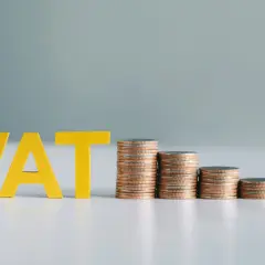 Złote litery VAT obok malejących stosów monet. Pamiętaj, do kiedy trzeba zapłacić podatek, aby uniknąć kar.