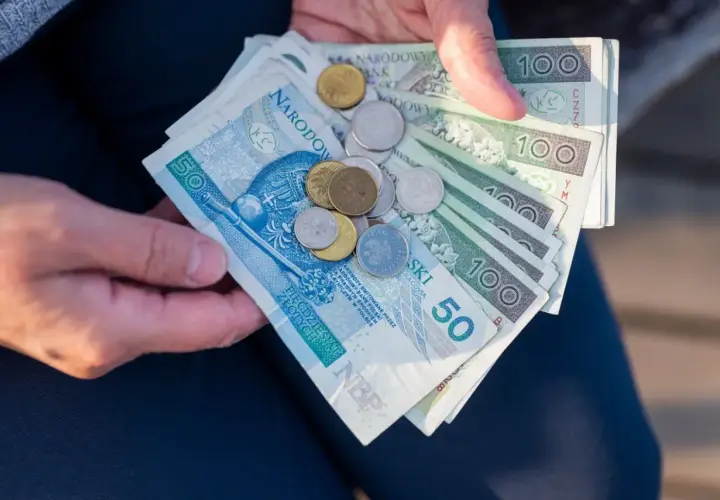 Dłonie trzymają polskie banknoty i monety. Czy mam 60 lat i 10 lat pracy, czy dostanę emeryturę?