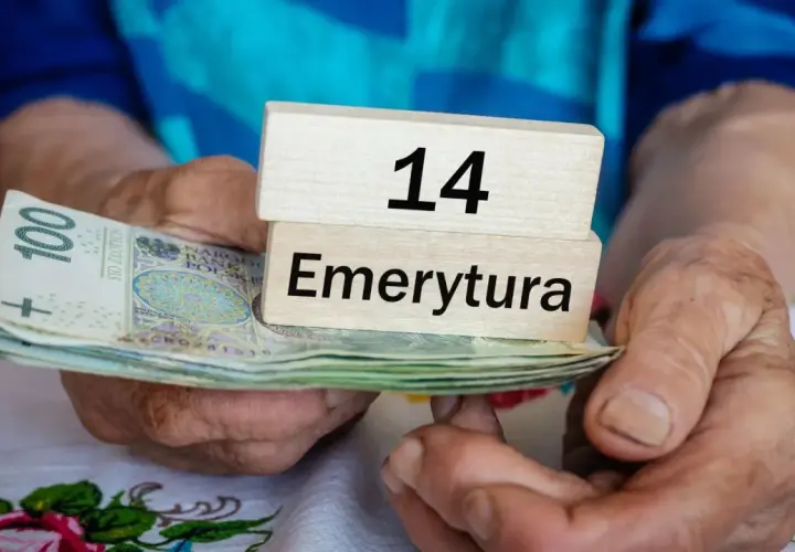 Dłonie trzymają stos banknotów i drewniane klocki z napisem "14 Emerytura".
