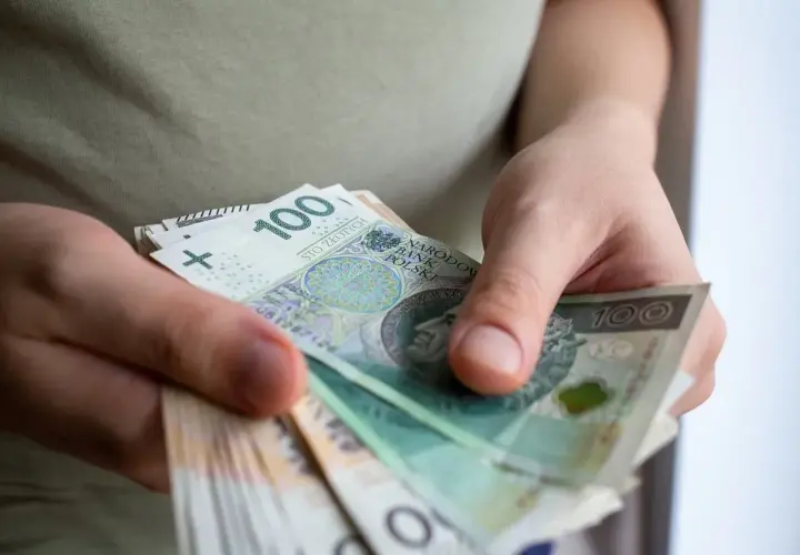 Dłonie trzymające stos banknotów 100 zł.