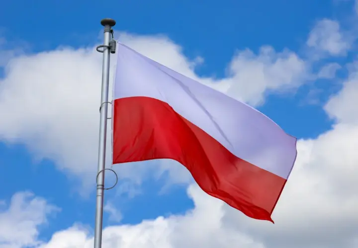 Biało-czerwona flaga Polski powiewa na tle błękitnego nieba z chmurami. Czy 2 maja jest wolny? To pytanie zadają sobie Polacy, ciesząc się świętem narodowym.