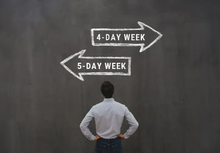 Mężczyzna stoi przed tablicą z dwoma strzałkami: "4-DAY WEEK" i "5-DAY WEEK".