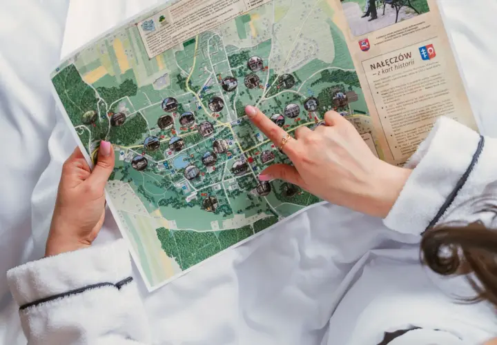 Dłoń wskazująca palcem na mapę Nałęczowa z zaznaczonymi atrakcjami.