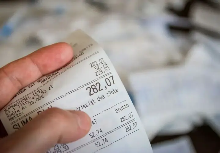 Dłoń trzyma paragon z widoczną kwotą 282,07 zł.