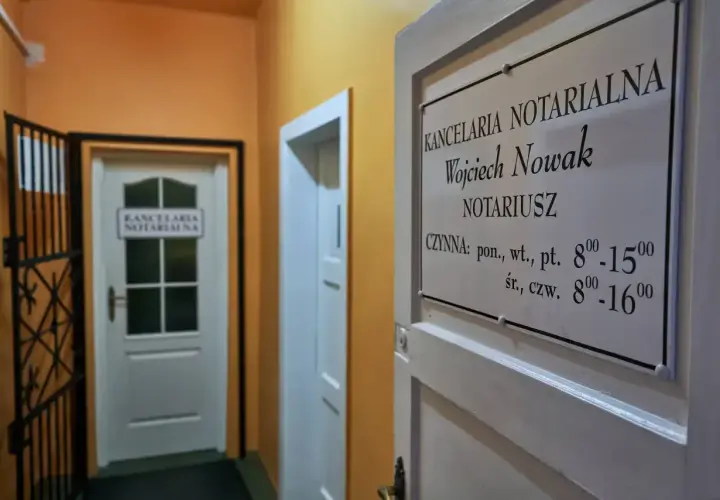 Tabliczka z nazwą kancelarii notarialnej Wojciecha Nowaka i godzinami otwarcia.