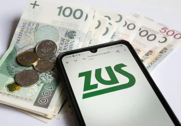 Telefon z logo ZUS na ekranie, obok polskie banknoty i monety.