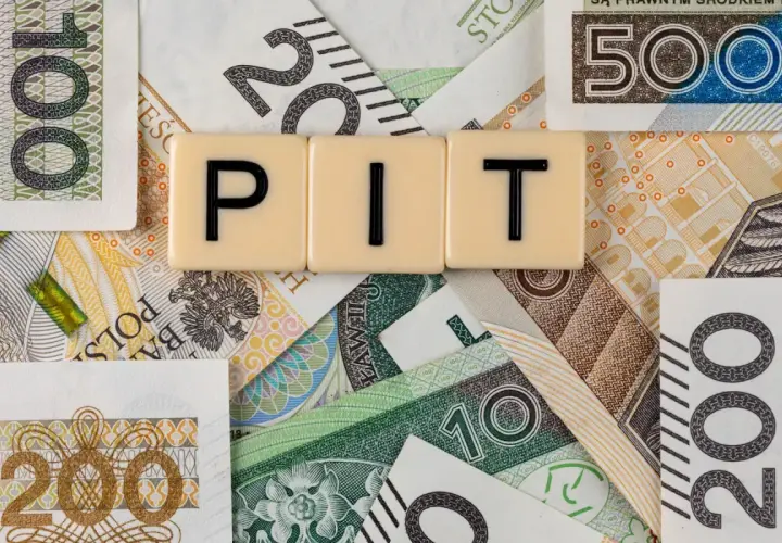 Rozliczenie dochodów z zagranicy przykład: litery PIT na tle polskich banknotów o nominałach 10, 20, 100, 200 i 500 zł.