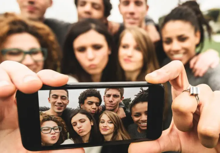 Grupa młodych ludzi robi sobie selfie telefonem.