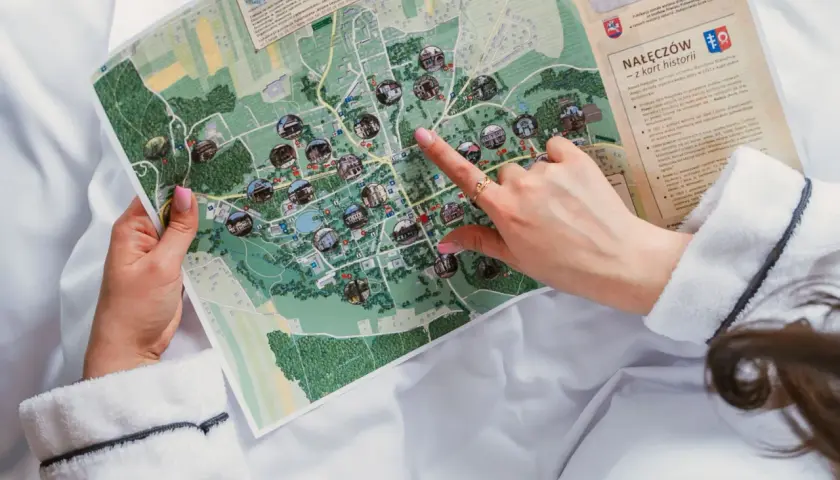 Dłoń wskazująca palcem na mapę Nałęczowa z zaznaczonymi atrakcjami.
