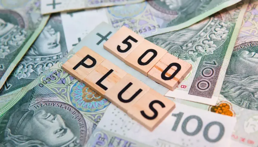 Litery "500 PLUS" na tle polskich banknotów. Symbol wsparcia finansowego, np. 500 plus dla niepełnosprawnych.