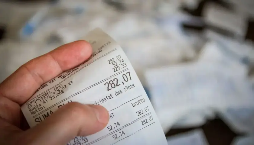 Dłoń trzyma paragon z widoczną kwotą 282,07 zł.
