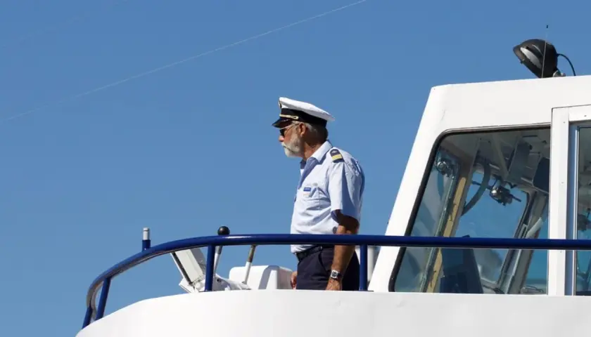 Kapitan na mostku statku, wpatrzony w dal. Zastanawia się, ile zarabia marynarz na jego stanowisku.