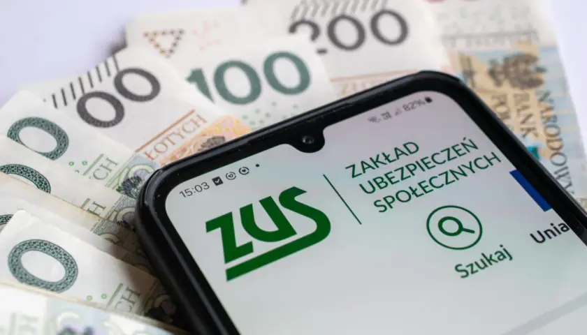 Telefon z aplikacją ZUS na tle polskich banknotów.