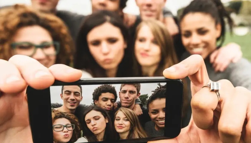 Grupa młodych ludzi robi sobie selfie telefonem.