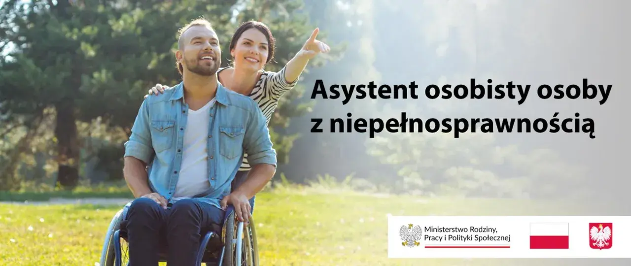 Uśmiechnięty mężczyzna na wózku inwalidzkim i kobieta wskazująca palcem w dal. Asystent osoby z niepełnosprawnością 2026.
