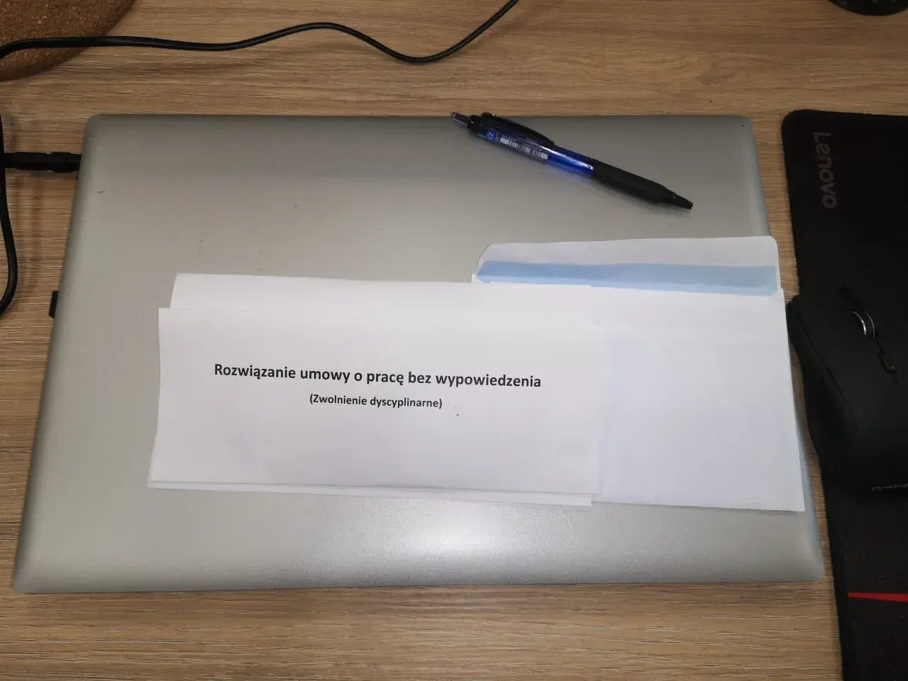 Dokument "Rozwiązanie umowy o pracę bez wypowiedzenia (Zwolnienie dyscyplinarne)" na laptopie z długopisem.