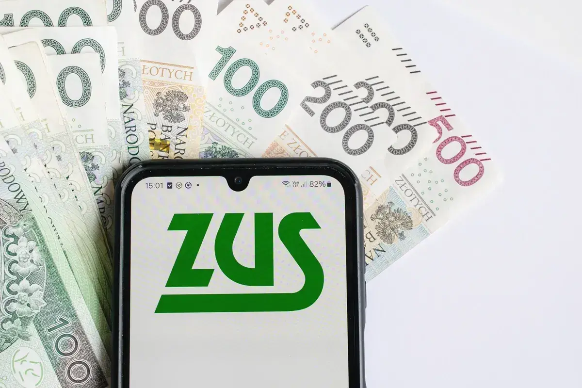 ZUS na ekranie telefonu, obok banknotów 100, 200 i 500 zł. Planowanie emerytury w Polsce.