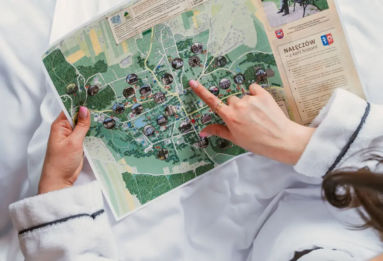 Dłoń wskazująca palcem na mapę Nałęczowa z zaznaczonymi atrakcjami.