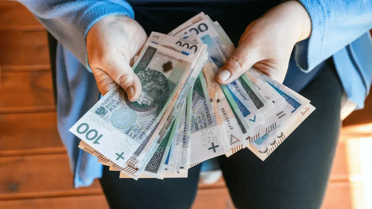 Dłonie trzymające plik polskich banknotów 100 zł.