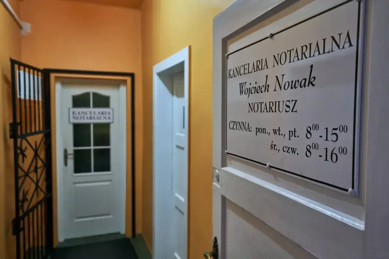 Tabliczka z nazwą kancelarii notarialnej Wojciecha Nowaka i godzinami otwarcia.