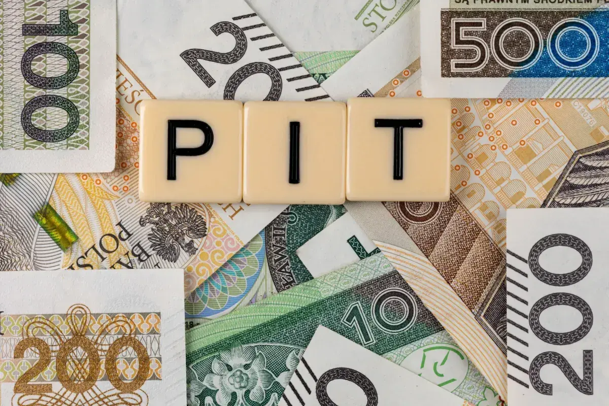 Rozliczenie dochodów z zagranicy przykład: litery PIT na tle polskich banknotów o nominałach 10, 20, 100, 200 i 500 zł.