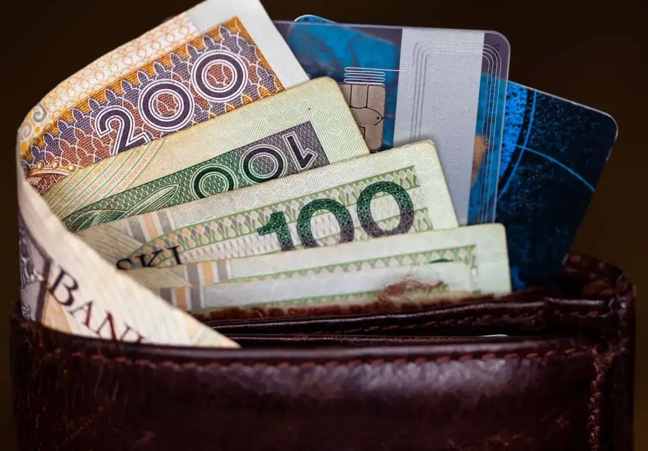 Portfel z polskimi banknotami (200 zł, 100 zł) i kartami płatniczymi.