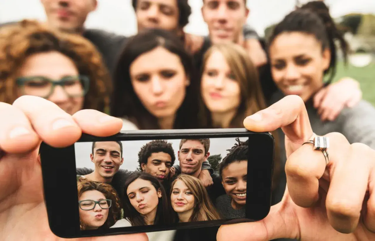 Grupa młodych ludzi robi sobie selfie telefonem.