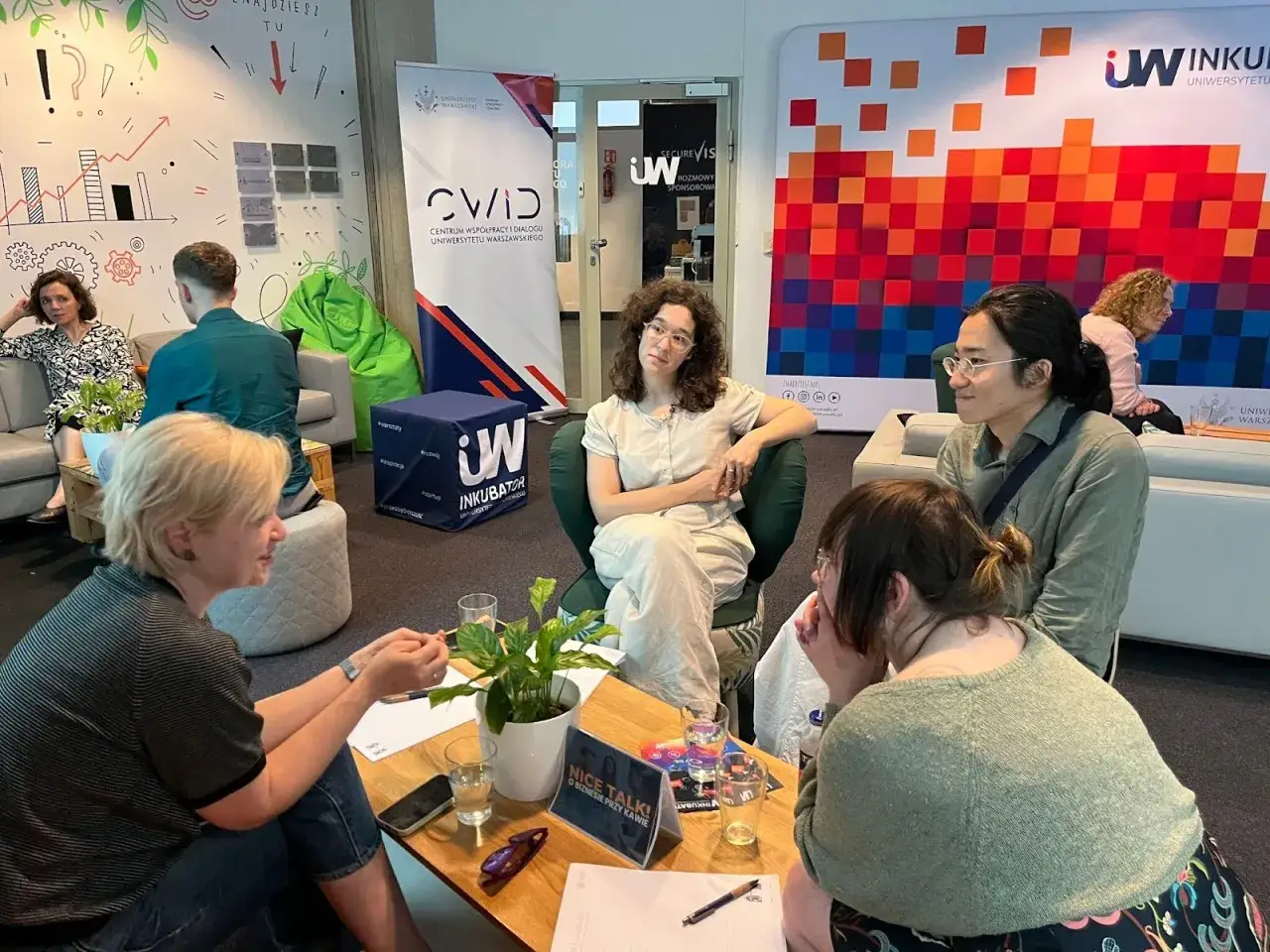 Grupa osób dyskutuje przy kawie, budując relacje i możliwości networkingowe.
