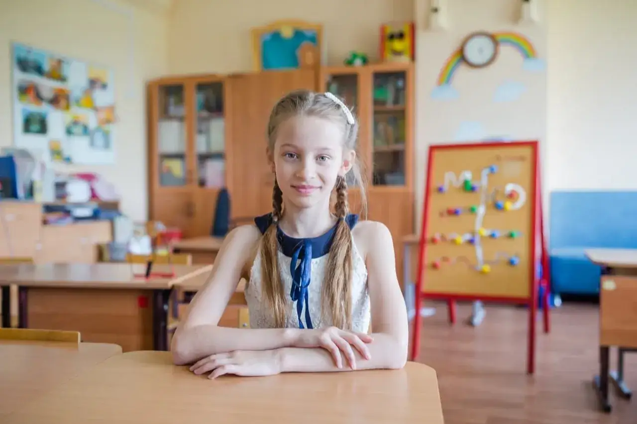 Uśmiechnięta dziewczynka w klasie. Orzeczenie o dysleksji otwiera drogę do wsparcia i lepszego zrozumienia jej potrzeb edukacyjnych.