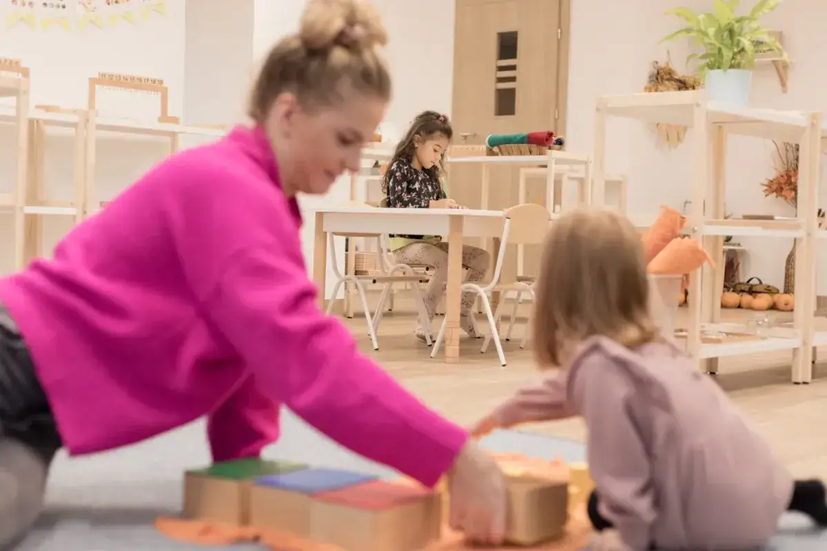 Nauczycielka pokazuje dzieciom, montessori co to jest, podczas zabawy klockami.